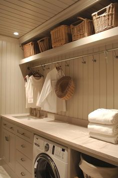 a washer and dryer in a white laundry room with baskets on the wall