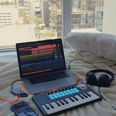 a laptop computer sitting on top of a bed next to headphones and an mp3 player