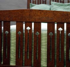 a wooden bed with green bedspread and pillows