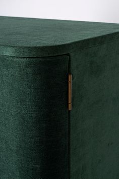 a close up view of the back of a green fabric storage unit with brass handles