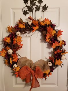 a wreath is hanging on the door with pumpkins and other autumn decorations around it