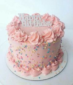 a pink birthday cake with sprinkles and the words happy birthday on top