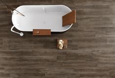 a bath tub sitting on top of a wooden floor next to a wall mounted phone