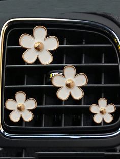 four white flowers are attached to the center console of a car's air vent