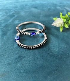 two silver rings with blue beads are sitting next to a flower