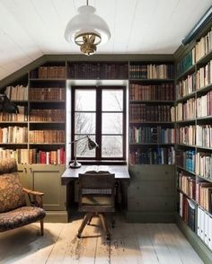 a room with many bookshelves and a desk in the corner, along with a chair