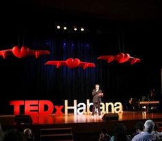 a man standing on top of a stage in front of a large screen with red paper birds