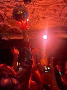 people are holding up their cell phones in the air at a party with disco balls