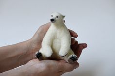 a small white polar bear sitting in someone's hand