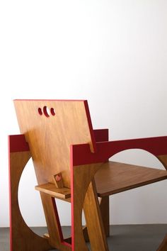 a wooden chair sitting on top of a floor next to a white wall with red trim