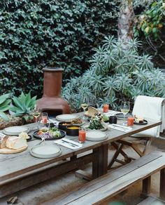 an outdoor table with plates and glasses on it