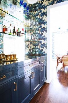 a kitchen with blue cabinets and floral wallpaper on the walls, along with wooden floors