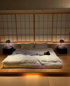 a large bed sitting in the middle of a room next to two lamps on either side of it