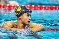 a boy swimming in the pool wearing a swim cap and goggles on his head