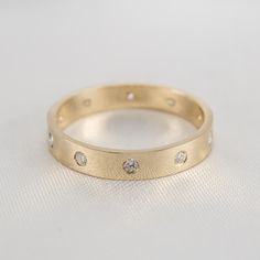 a yellow gold ring with three diamonds on the inside and outside, sitting on a white surface