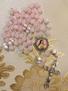 Handmade light pink Jade gemstone St. Thérèse of Lisieux Rosary beads with ceramic floral Our Father beads. Made with a silver Fleur de Lis crucifix and round color enamel St. Thérèse center. Affordable Handmade Pink Rosary, Pink Rose Quartz Jewelry With 8mm Beads, Pink Spiritual Jewelry With 8mm Beads, Pink Polished Beads Spiritual Jewelry, Pink Beaded Jewelry With 8mm Round Beads, Pink Round Beaded Jewelry 8mm, Pink Round 8mm Bead Jewelry, Pink Rosary With 8mm Round Beads, Pink Beaded Rosary With Round Beads