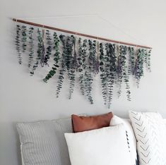 a bed with pillows and plants hanging on the wall