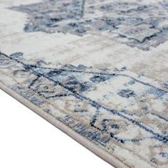 a blue and white area rug with an ornate design on the bottom, in front of a white background