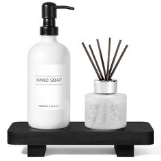 a soap dispenser, candle holder and reeds on a black shelf