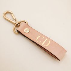 a leather keychain with the letter d on it and a gold metal hook