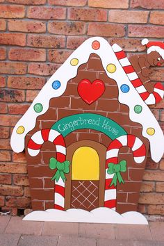 a cardboard gingerbread house on the side of a brick wall with candy canes