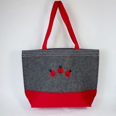 A sturdy red and grey colorblock felt tote with riveted web handles and three red and black Ladybugs embroidered on the front and back of the tote. Made out of 100% polyester felt and is approximately 12 inches tall by 12 inches wide by 4.5 inches deep. Wipe clean with a damp cloth. A fun tote to carry almost anything. Embroidered in the USA!  This item can be personalized with custom embroidery underneath the Ladybugs on the front and back of the tote. Embroidered School Tote Canvas Bag, Ladybug Felt, Embroidered Canvas Bag, Black Ladybug, Felt Tote, Beach Shopping, Lady Bugs, Embroidered Canvas, Personalized Embroidered