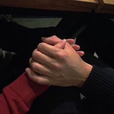 two people holding hands while sitting at a table with their arms folded over each other