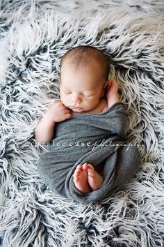 a baby wrapped in a blanket on top of a fluffy rug