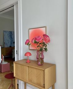 pink flowers are in a vase on a dresser