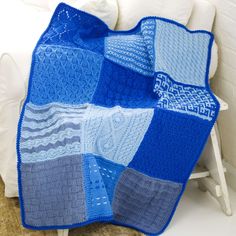 a crocheted blanket sitting on top of a bed next to a white chair