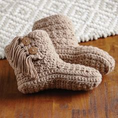 a pair of crocheted boots sitting on top of a wooden floor next to a rug