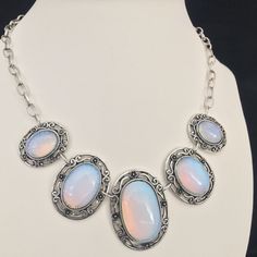 Moonstone Oval Cabochons Silvertone Choker Necklace Lovely oval cabochons set in silver tone metal oval base framed with swirls and floral motifs.  For size and length/drop information refer to image with ruler. Images forms part of the description so please look carefully and ask any questions.  Happy to respond to all queries. Fast and fully trackable shipping. Silver Oval Gemstone Cabochons, Oval Cabochon Costume Jewelry Necklace, Silver Oval Costume Jewelry Necklace, Ornate Silver Necklace With Cabochon, Ornate Silver Cabochon Necklace, Silver Oval Cabochon Jewelry With Natural Stones, Silver Jewelry With Oval Cabochon Natural Stones, Ornate Silver Oval Cabochon Jewelry, Silver Oval Cabochon Jewelry With Stones