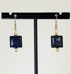 "- Exciting Lapis Lazuli Beaded Gemstone Earrings in a 1/2\" Puff Square design with 14K Gold Filled Corrugated Tiny Saucer Beads and 14K Gold Filled Shepherd (or Bali) Hook Ear Wires. See Photos #1-3. - Deep or Royal Blue shade with hints of Gold flecks. - Accented with 2 14K Gold Filled Saucer Corrugated Beads in 3.5mm x 2.5mm size, top & bottom. - 14K Gold Filled Bali (or Shepherd) Hook Ear Wires with Ball Ends. - See same Earring in 14K Gold Filled Studs or Posts with 4mm Ball Ends and Backs Elegant Earrings With Gemstone Beads, Gold Gemstone Bead Drop Earrings, Gold Drop Earrings With Gemstone Beads, Elegant Gemstone Beaded Earrings For Gift, Elegant Adjustable Beaded Earrings With Gemstone Beads, Artisan Polished Beads Earrings As Gift, Rectangular Gemstone Beads Gold Jewelry, Artisan Earrings With Polished Beads For Gift, Gold Rectangular Gemstone Beads Jewelry