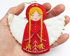 a hand holding a small red and white angel ornament