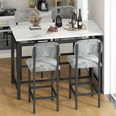 a kitchen table with four chairs and two bottles of wine on top of it in front of an oven