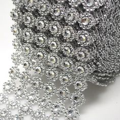 a roll of silver beaded ribbon on a white surface with lots of beads hanging from it