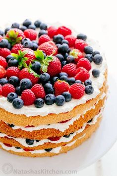 a cake topped with berries and blueberries on top of a white plate