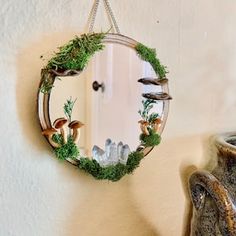 a mirror hanging on the wall next to a potted plant and mushroom decoration in front of it