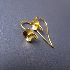 two pairs of gold - plated earrings on a blue surface