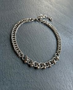 a silver chain bracelet with small beads on the clasp and an oval link around it