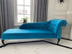 a blue chaise lounge chair sitting in front of a window