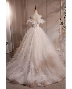 a white wedding dress on display in front of a mannequin headdress