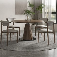 a round dining table with four chairs and a plant in the center, on a rug