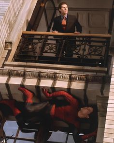 a man standing on top of a balcony next to spider - man figures in front of him