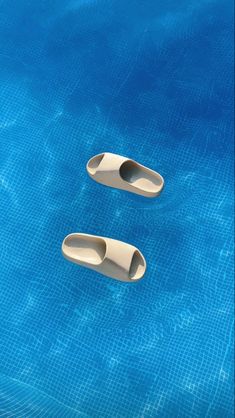 two white objects floating on top of a blue swimming pool