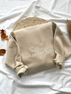 - love never fails- embroidered sweatshirt 👚MATERIAL - We use Gildan as our blanks. If the color purchased isn't available, I may sometimes use a different brand (more premium). Gildan Heavy Blend are 50/50 polyester and cotton. ▪️ SIZE - Please check the size chart before you purchase. 💧 CARE: Machine wash cold, inside-out, gentle cycle with mild detergent and similar colors. Tumble dry low, or hang-dry for longest life. All shirts are made to order, it is impossible to make sweatshirts ident Faith Apparel, Jesus Sweatshirts, Faith Clothing, Womens Sweatshirts, Flat Lay Photography, Sweatshirt For Women, Fashion Photography Inspiration, Love Never Fails, Embroidered Sweatshirt