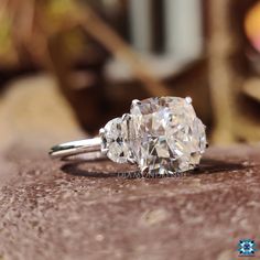 a three stone diamond ring sitting on top of a rock