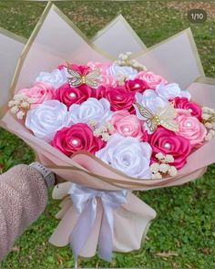 a person holding a bouquet of pink and white flowers in it's hand on the grass