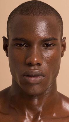 a close up of a man with no shirt on posing for a photo in front of a beige background