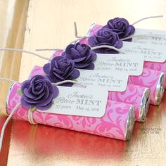 three candy bars decorated with purple flowers on top of a wooden table and tied in twine